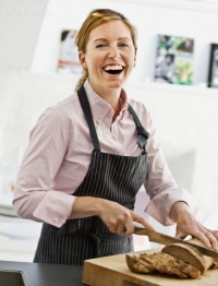 Smiling woman cutting bread in kitchen